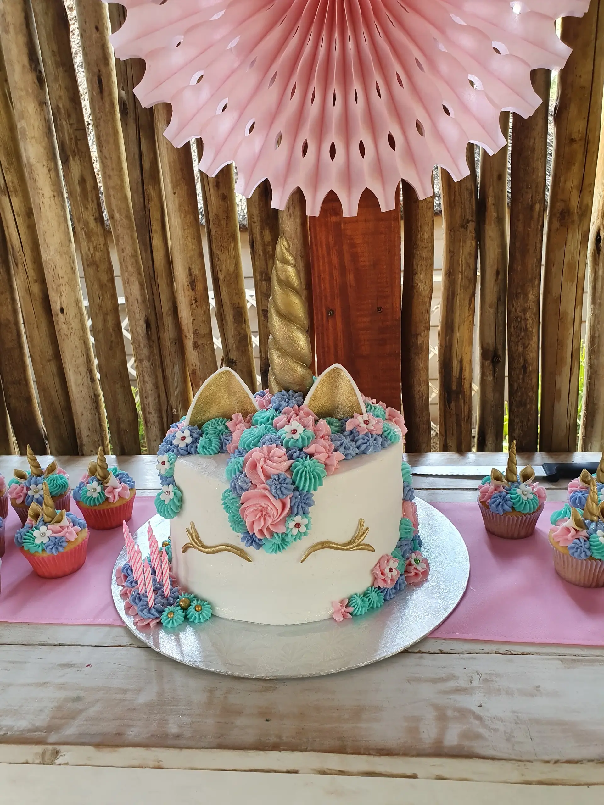 A unicorn cake and cupcakes on the snack table